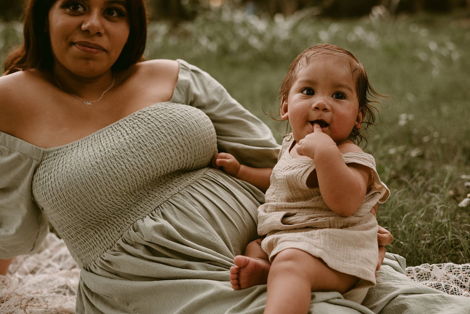 A joyful outdoor portrait shows parent and baby sharing a sweet moment on white lace.