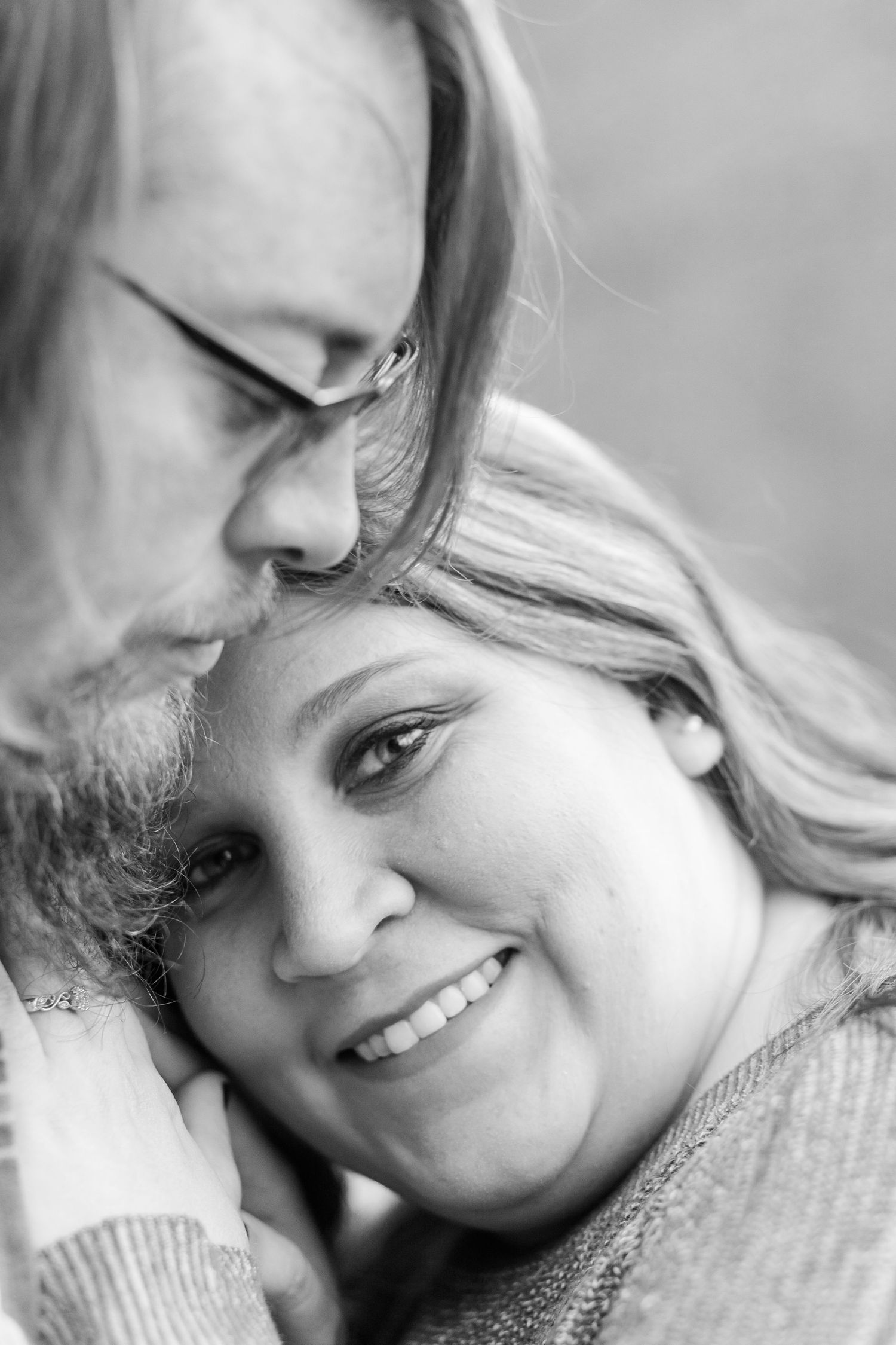 Close-up black and white portrait showing tender emotional moment between two people.