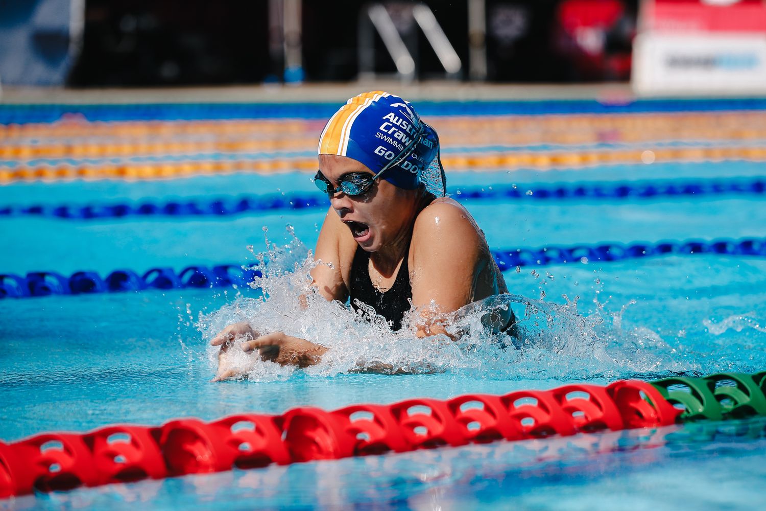 Competitive swimmer performing breaststroke during race in indoor pool.