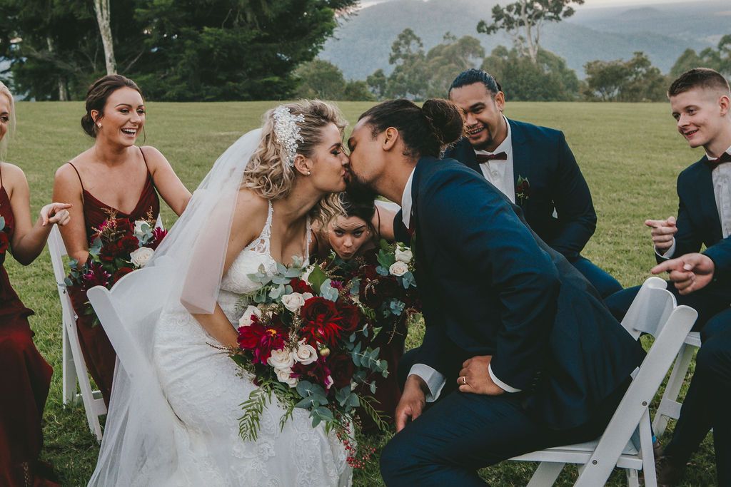 Wedding couple sharing a romantic moment during outdoor ceremony with guests looking on.