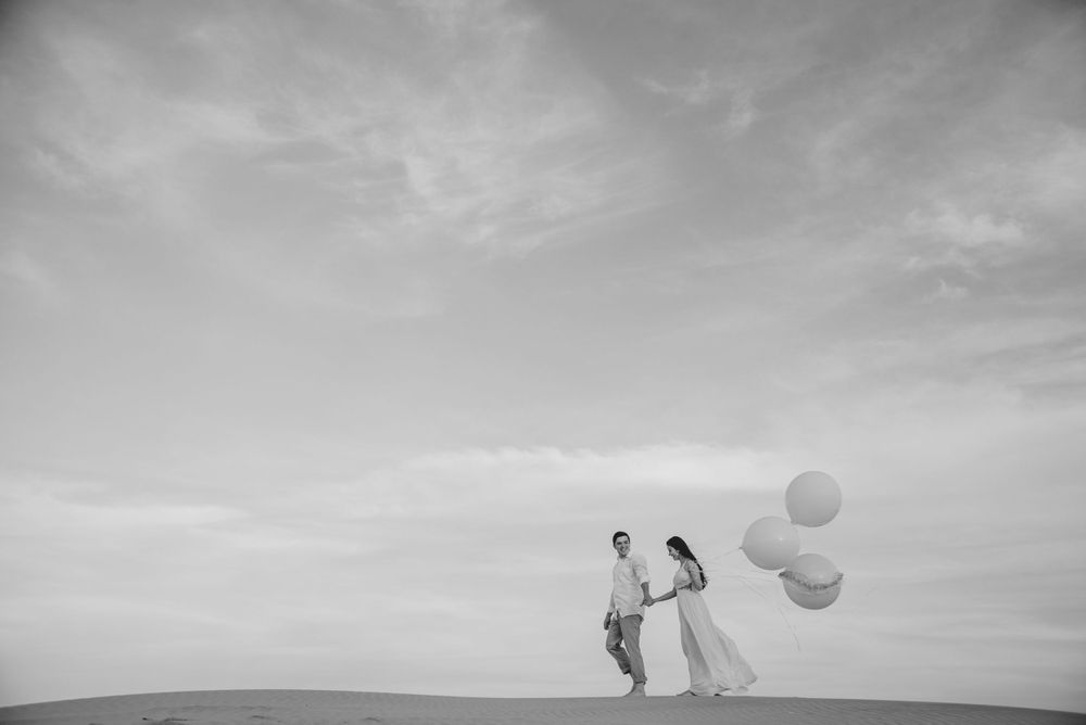 couple walking with balloons. black and white. sky. south padre island. wedding photographer