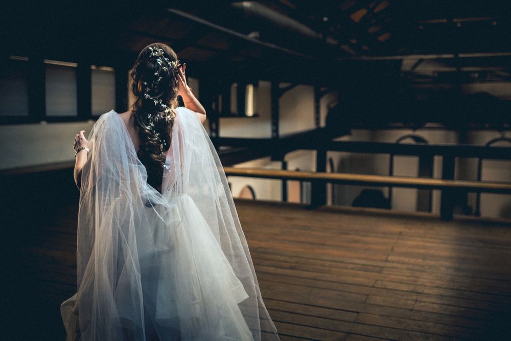 Dramatic backlit shot of flowing wedding dress in industrial warehouse setting.