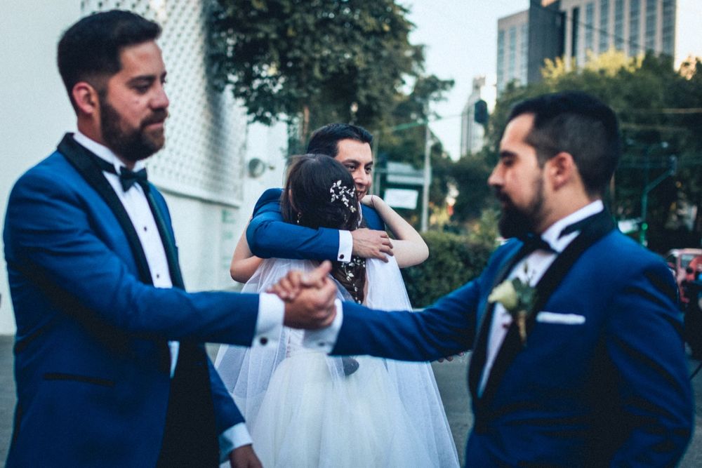 Wedding party members in navy suits sharing a celebratory moment outdoors.