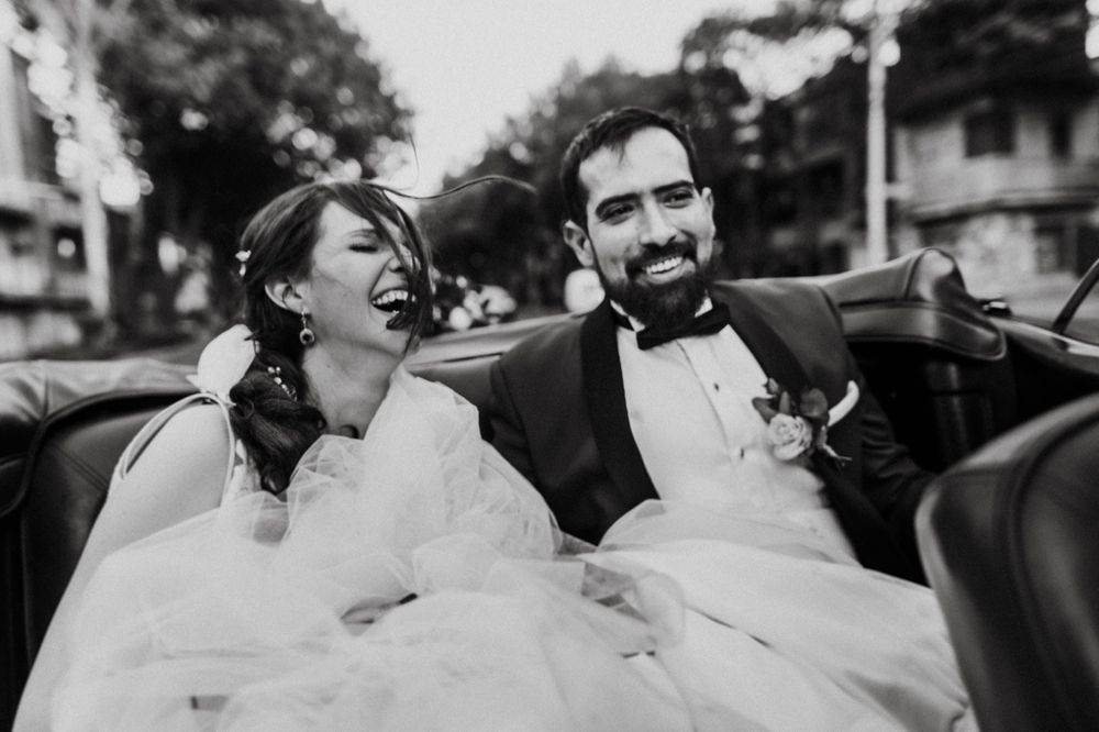 A joyful candid moment captured in black and white of newlyweds laughing together.