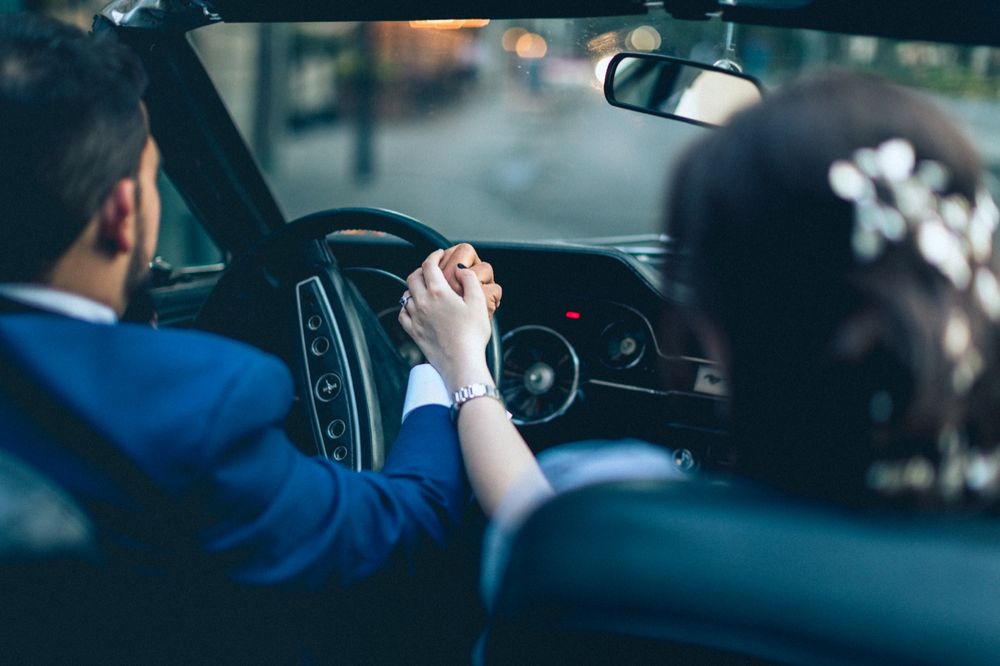 Interior view of couple holding hands while driving in a luxury car.