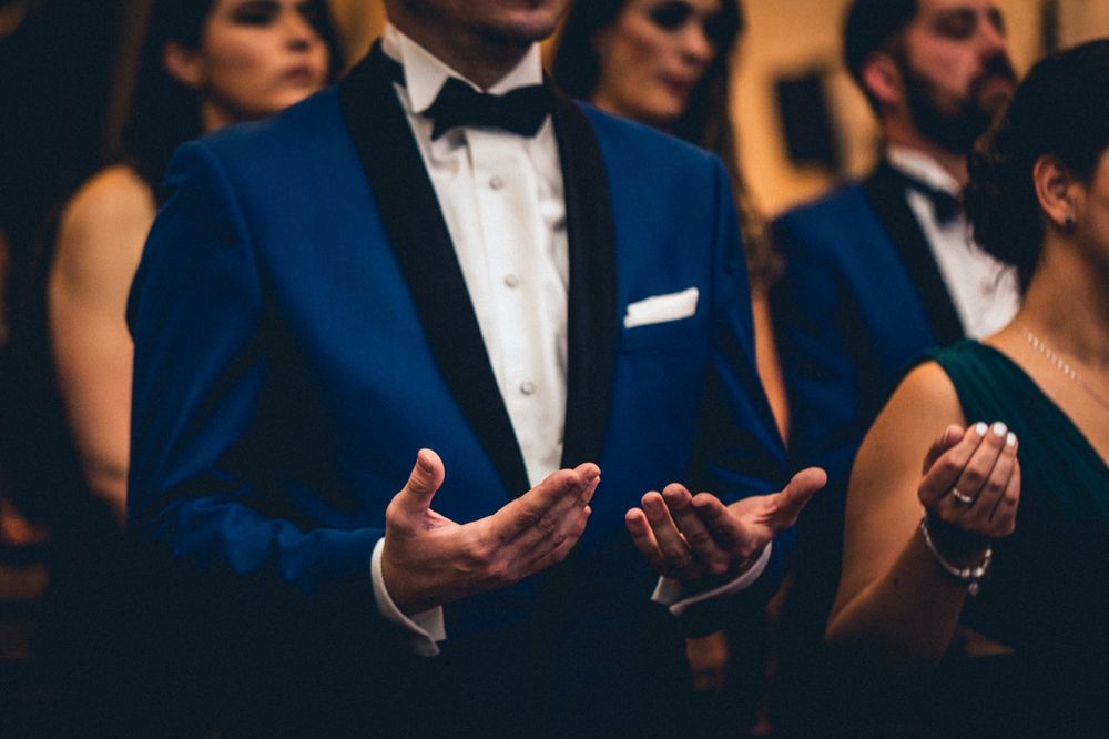 Wedding guests in formal attire applauding during an elegant indoor ceremony.