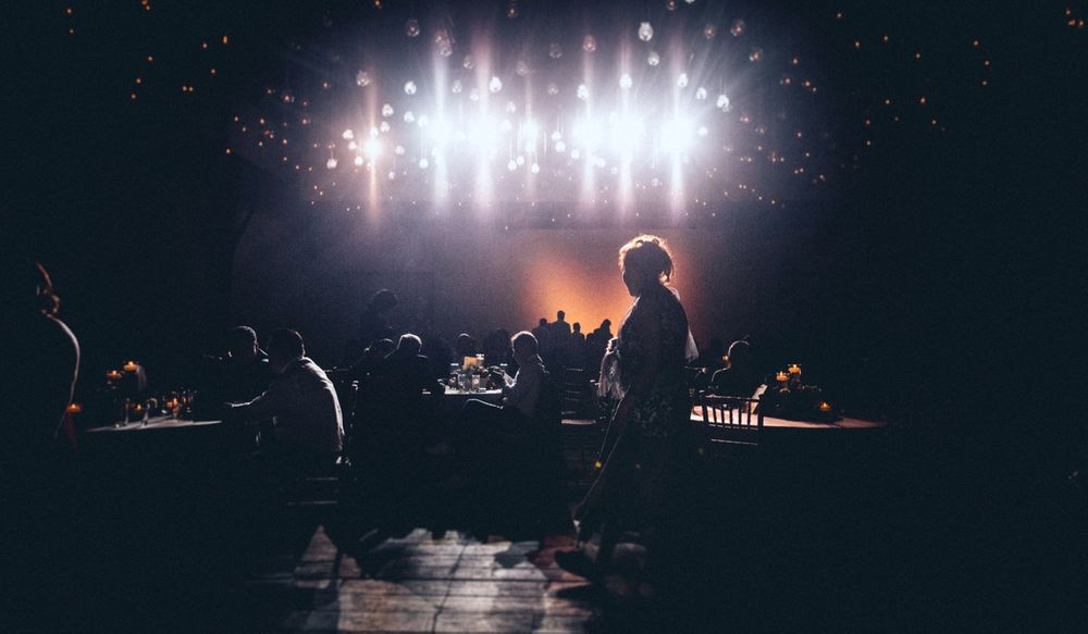 A stage illuminated by bright spotlights creating dramatic lighting effects in a dark venue.