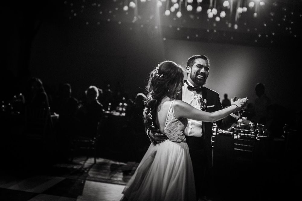 Black and white photo of joyful couple dancing together at wedding celebration.