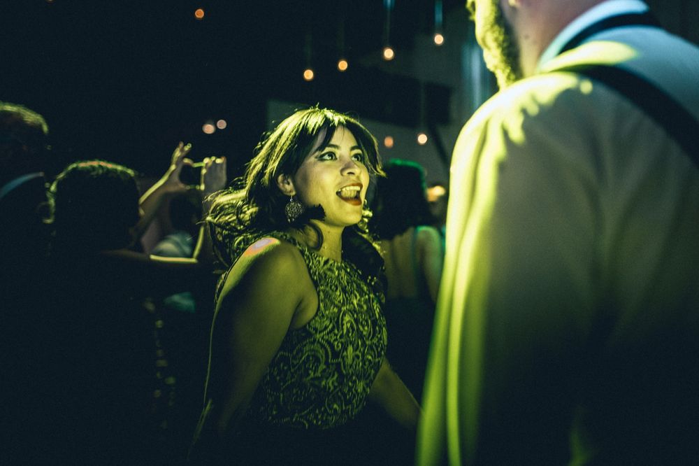 Guest in green dress dancing energetically at nighttime wedding reception.