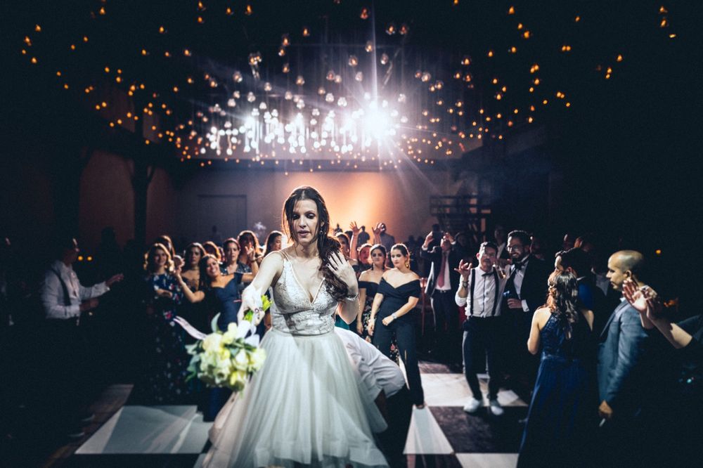 A bride in a white ball gown dances under dramatic lighting at her wedding reception.