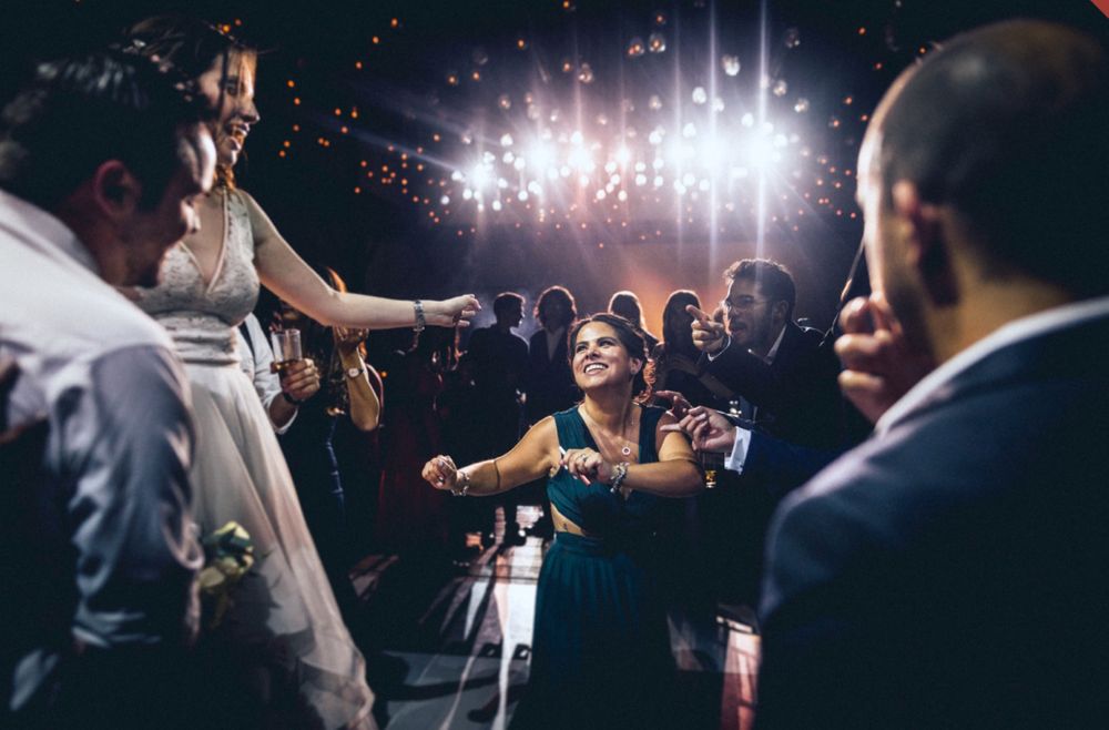 Wedding reception dance party with dramatic lighting and silhouettes of guests celebrating.