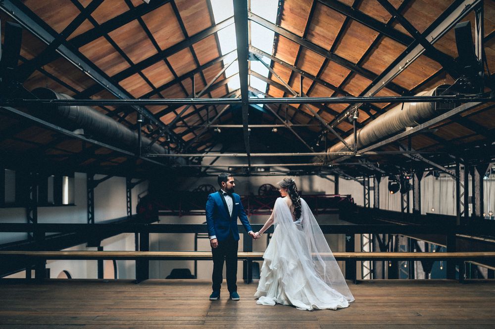 Panoramic view of an industrial warehouse venue with wedding couple in the distance.