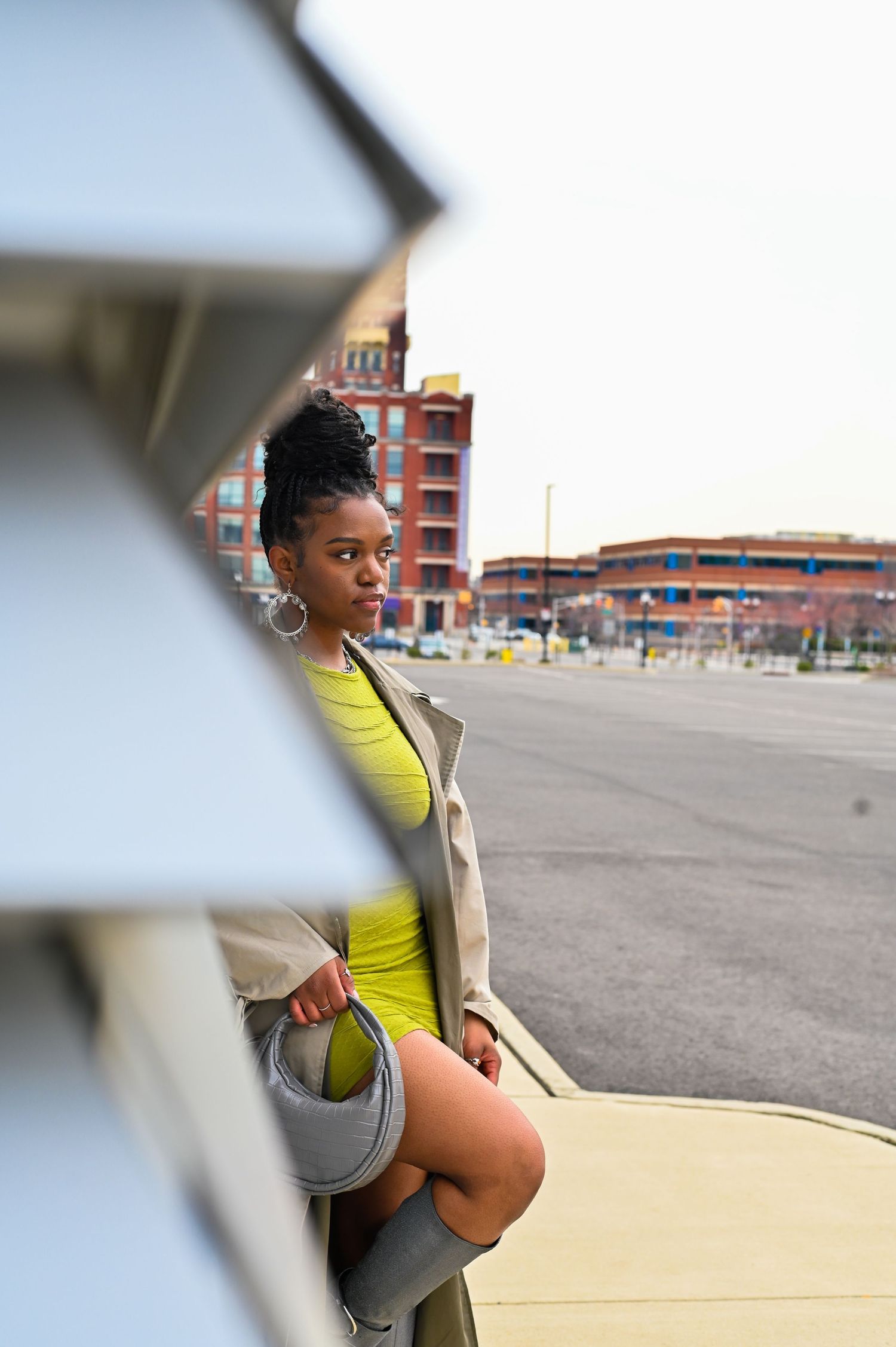 Fashion portrait through geometric frame showing green dress and beige coat against urban backdrop in Greater Philadelphia/South New Jersey.