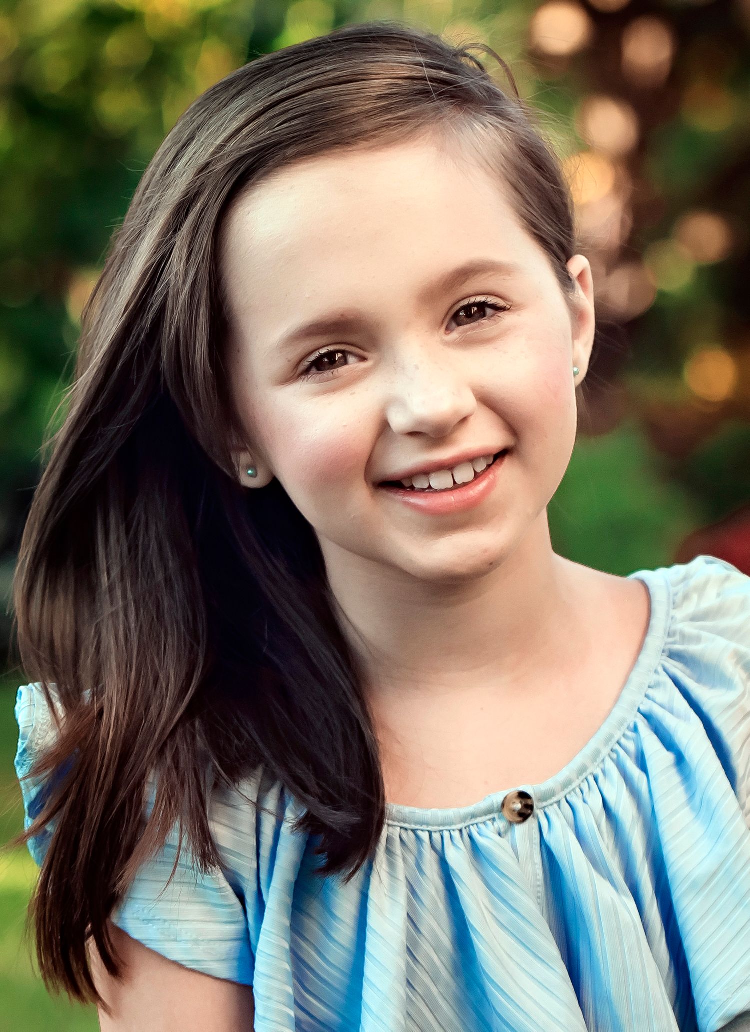 Outdoor portrait in blue top with natural bokeh background.