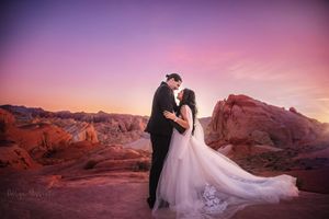 Romantic wedding portrait on red rocks during purple sunset.