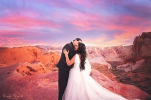 A romantic wedding photo against red rock formations during a dramatic pink and purple sunset.