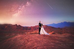 Wedding couple silhouetted against stunning Milky Way and mountain landscape at dusk.