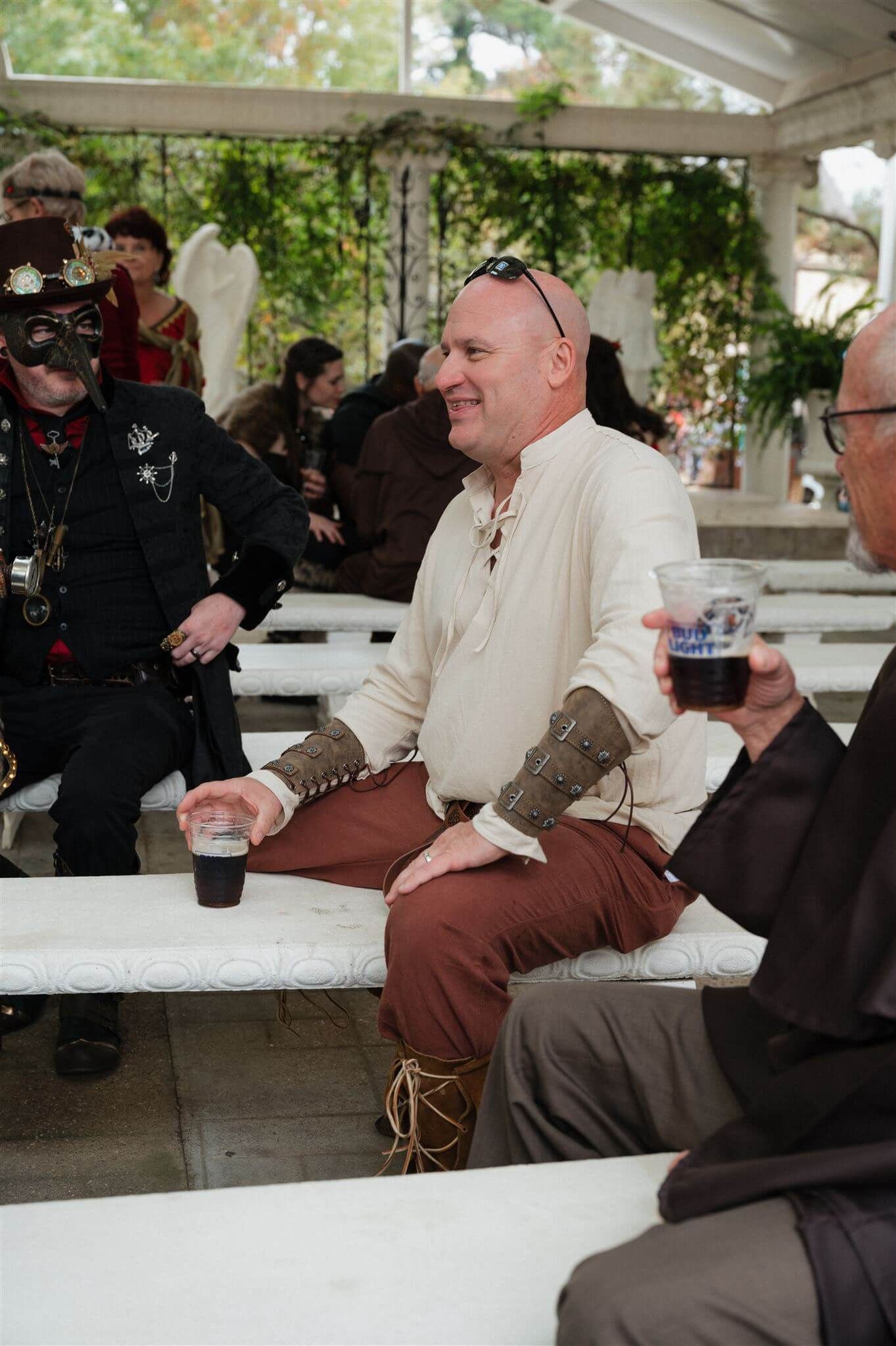 Gathering of festival attendees in medieval and renaissance attire seated on benches.