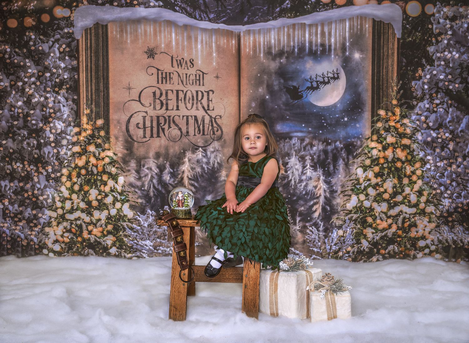 Toddler girl in green silk dress sitting on bench in front of Night Before Christmas book background