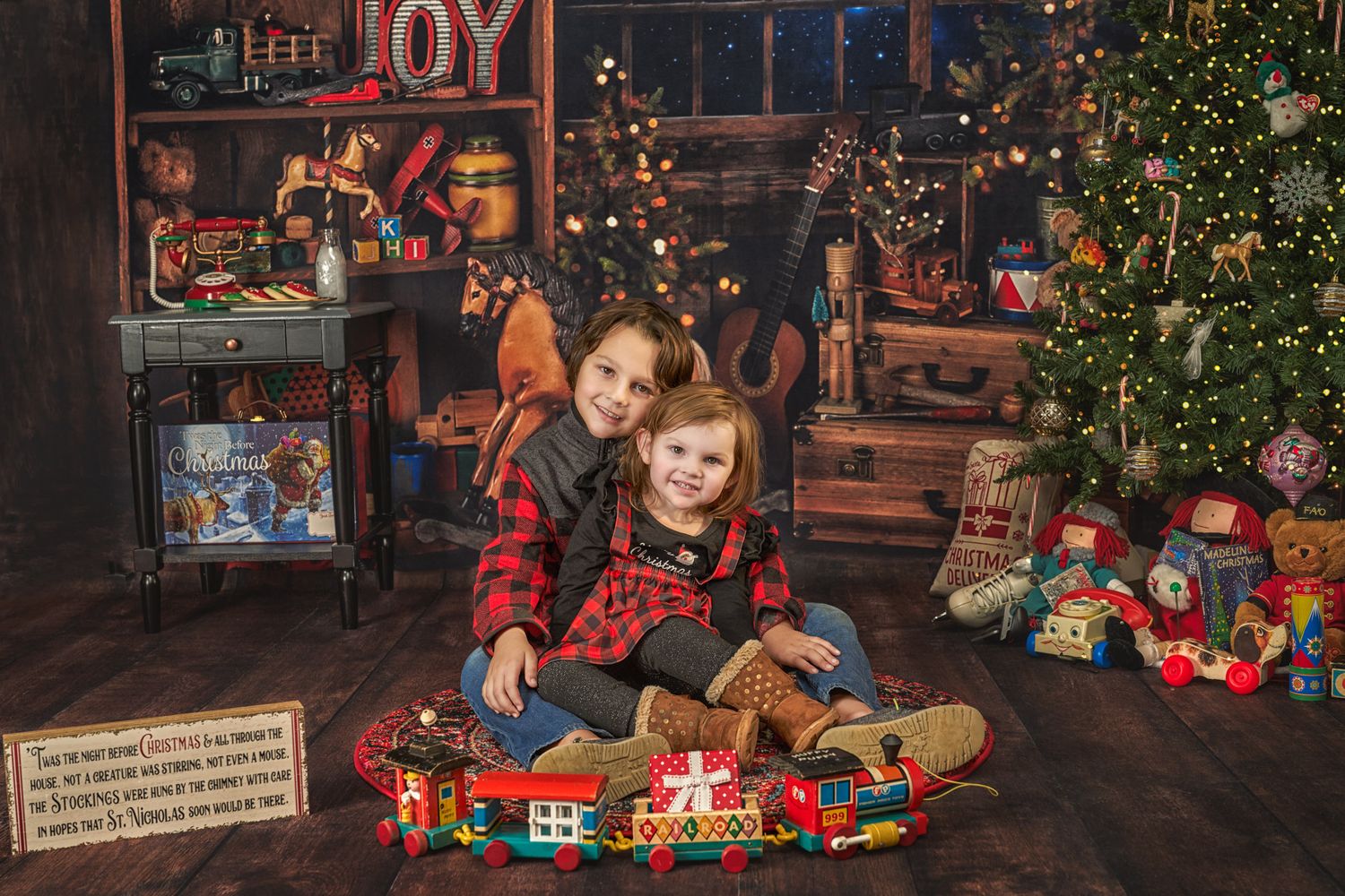 Boy and his younger sister on floor of Christmas scene