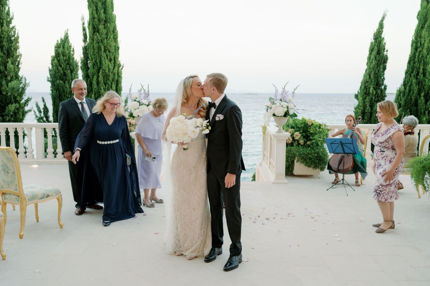 Intimate wedding moment captured on a coastal terrace surrounded by family and friends.