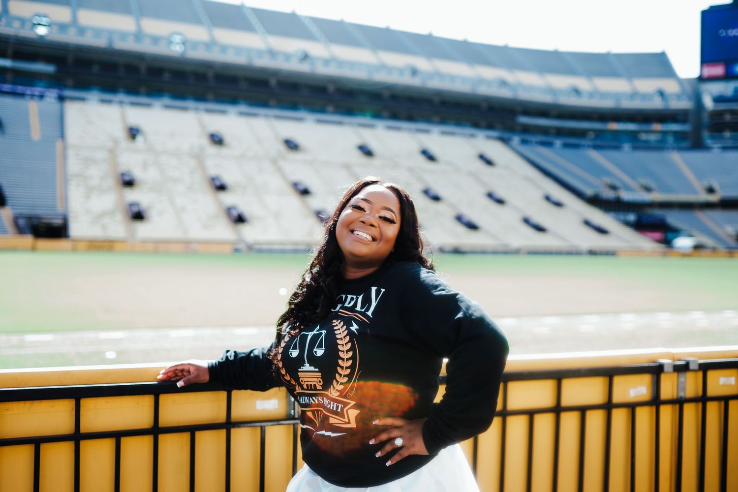 Athletic figure poses confidently against stadium seating backdrop at a football field.
