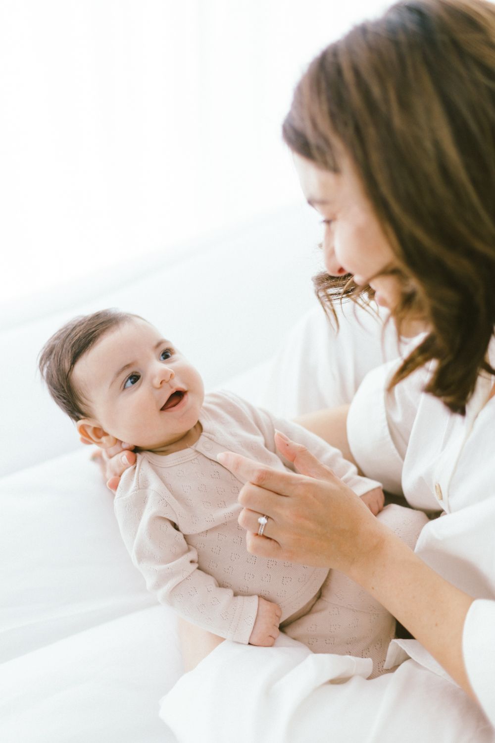 Joyful interaction between parent and smiling baby in bright setting.