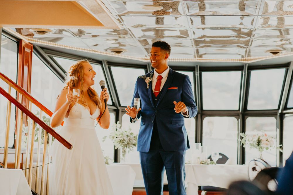Bride and groom sharing a joyful moment during champagne toast at wedding reception on a boat.