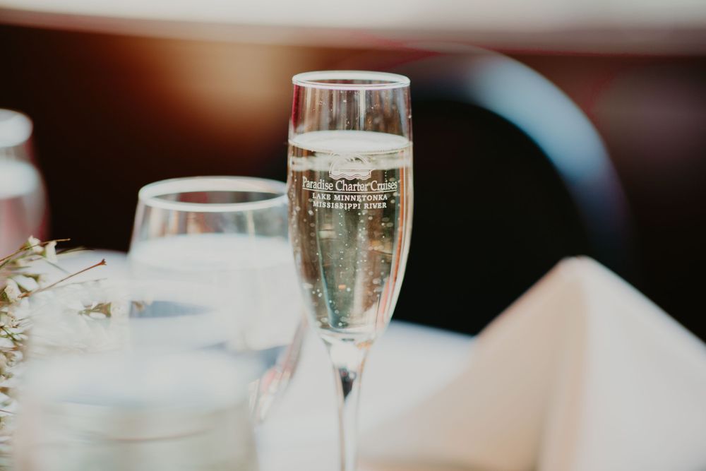 Elegant champagne flute with engraved logo at a wedding reception table setting.