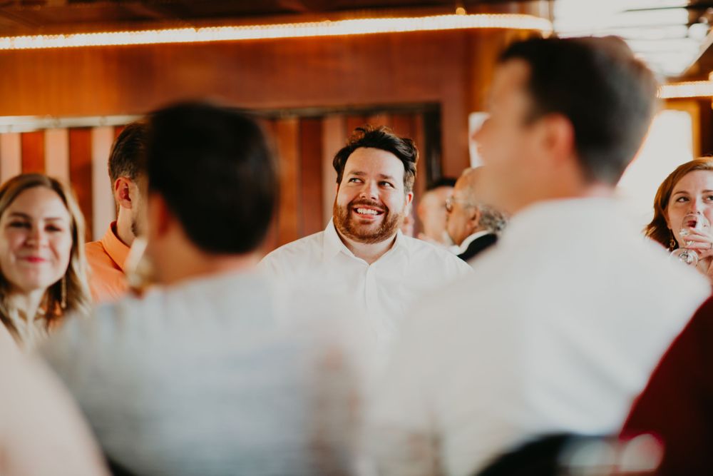 Happy male wedding guest smiling broadly while mingling at a wedding reception.