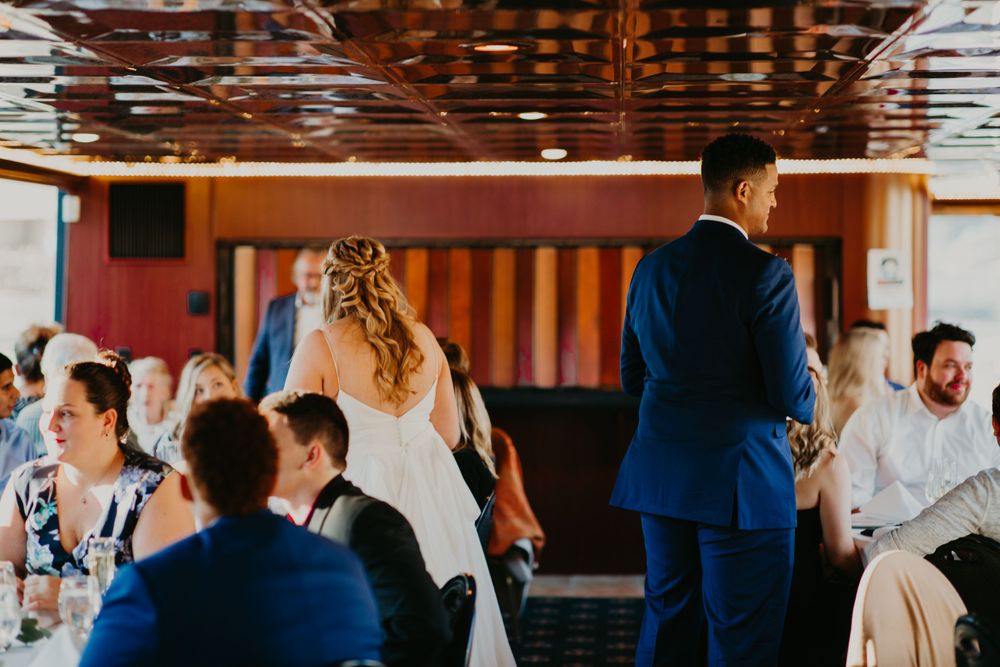 Bride and groom walking through wedding reception guests on a boat venue.