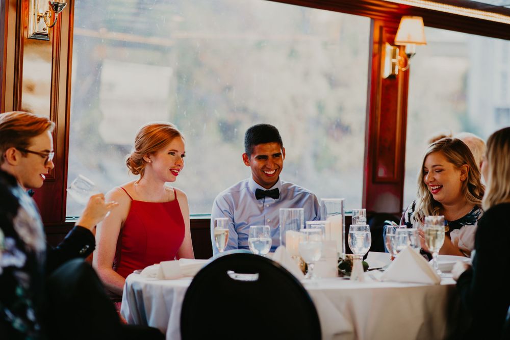 Wedding guests laughing and chatting at a decorated reception table on a boat.