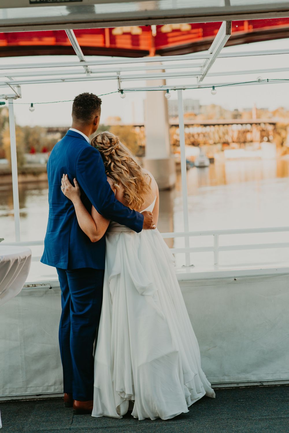Bride and groom embrace while gazing at the waterfront view at their wedding reception.