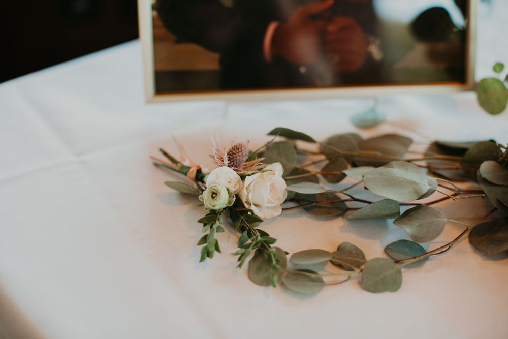 Elegant white floral wreath with eucalyptus displayed on a white tablecloth at a wedding.