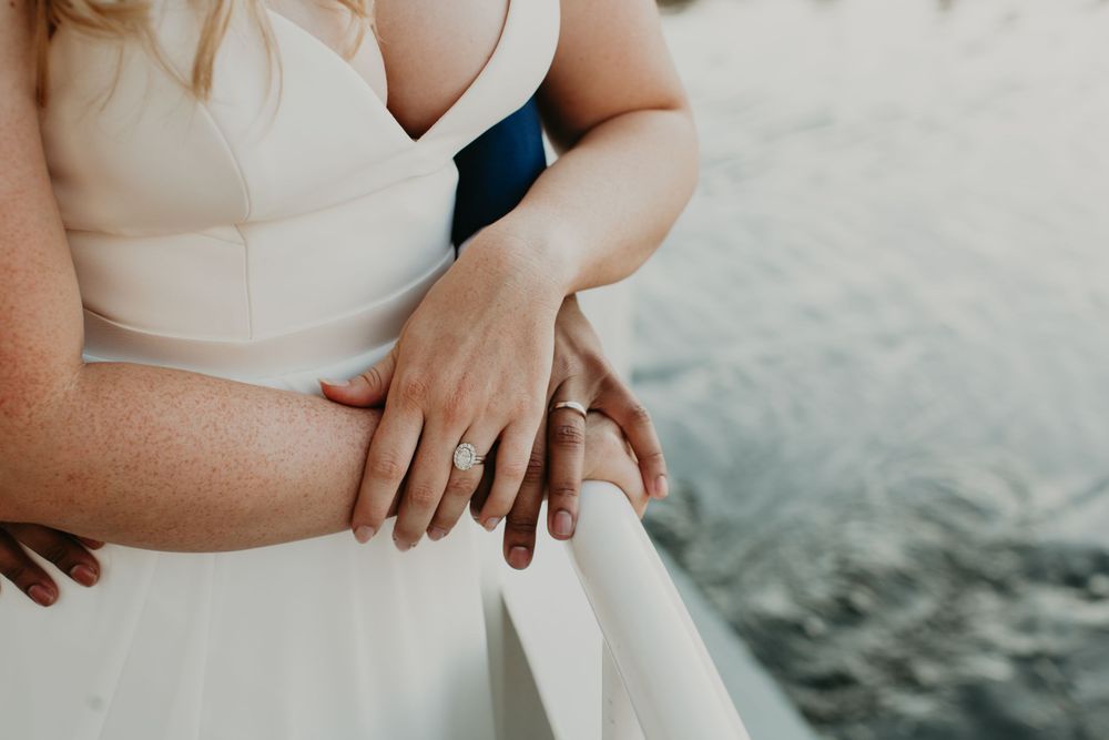 Close-up of bride and grooms hands with wedding rings on a boat railing.