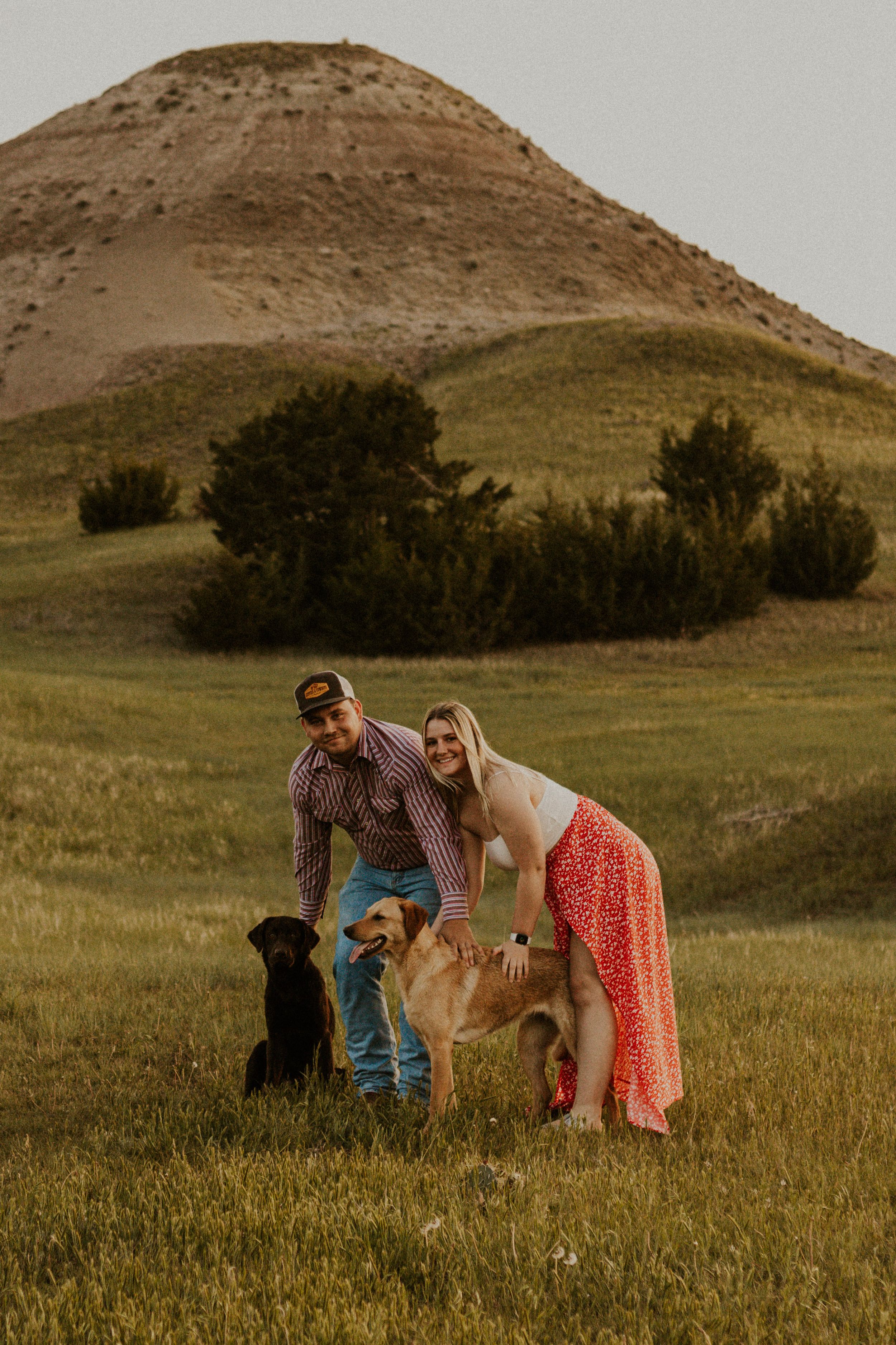 Couple poses with two Labrador retrievers in badlands.