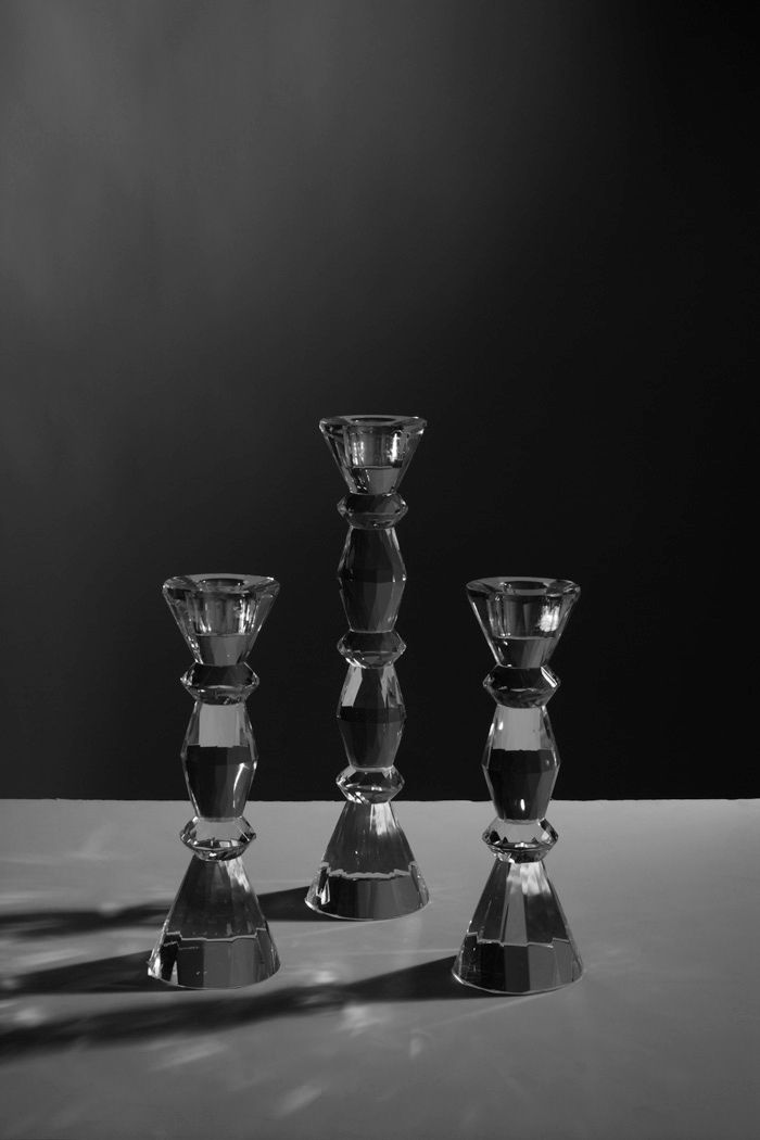 Three glass candlesticks arranged on a plain surface in monochrome.