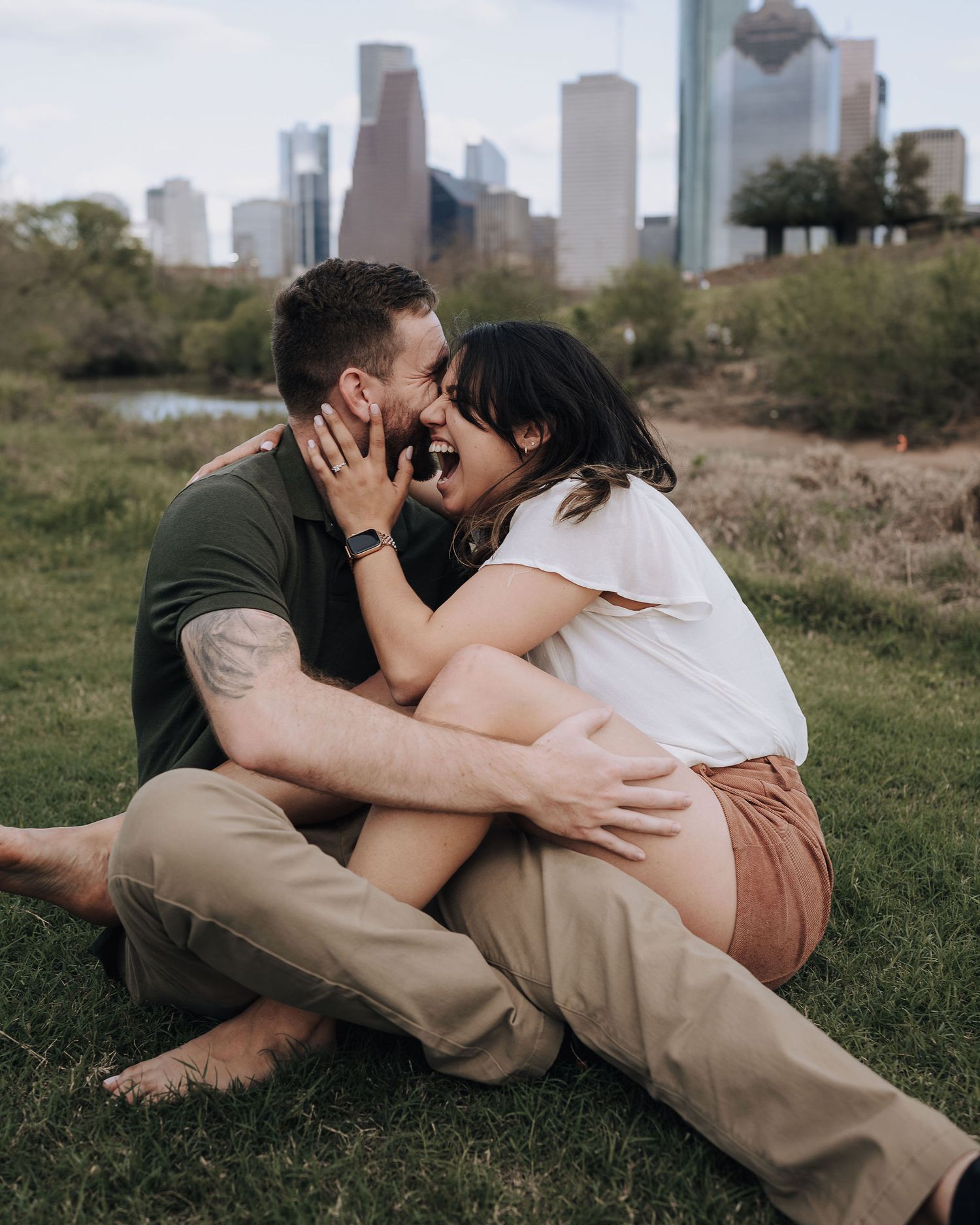 A couple shares a romantic moment with Houston skyline visible in background.
