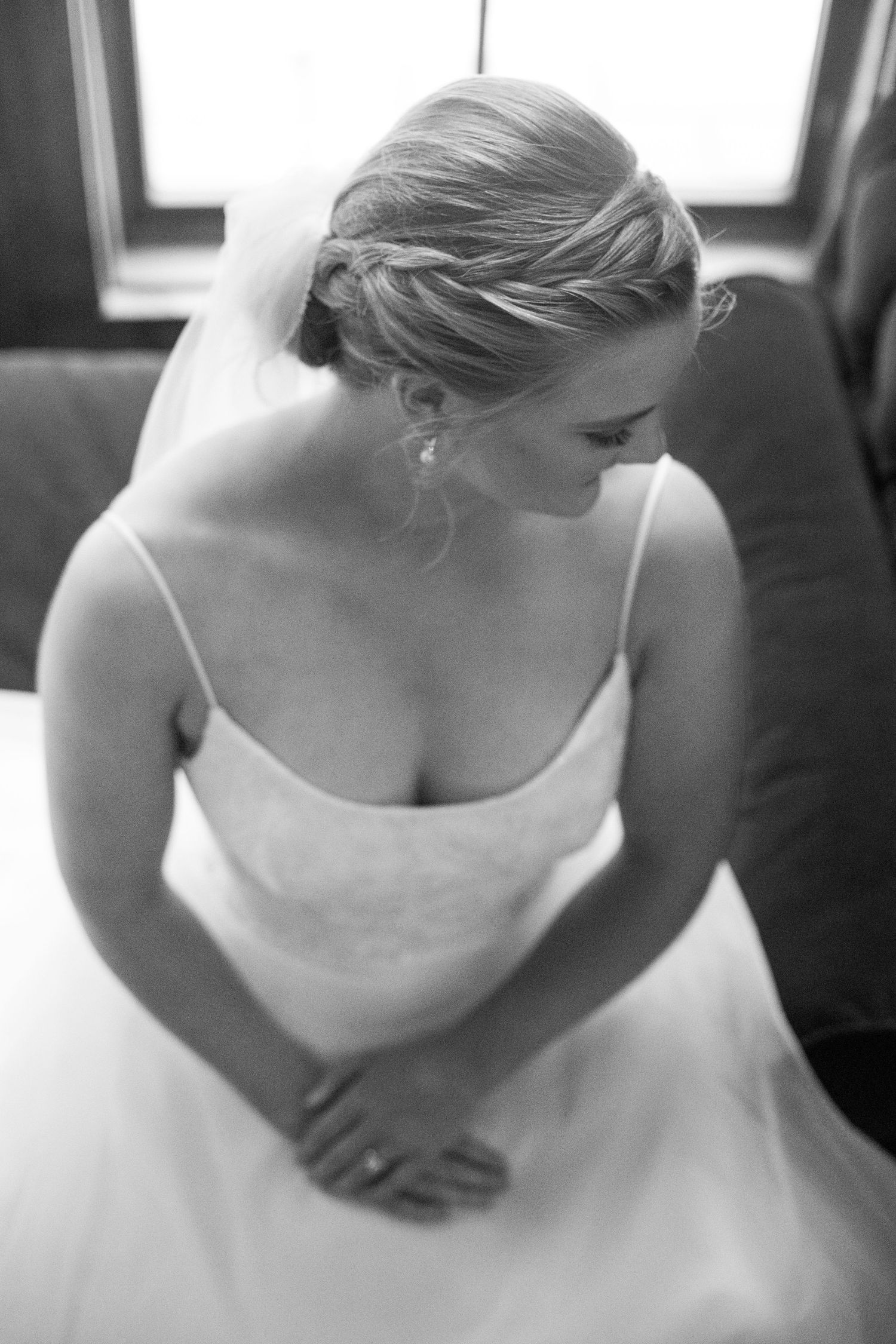 Elegant white wedding dress details shown in soft black and white photography.