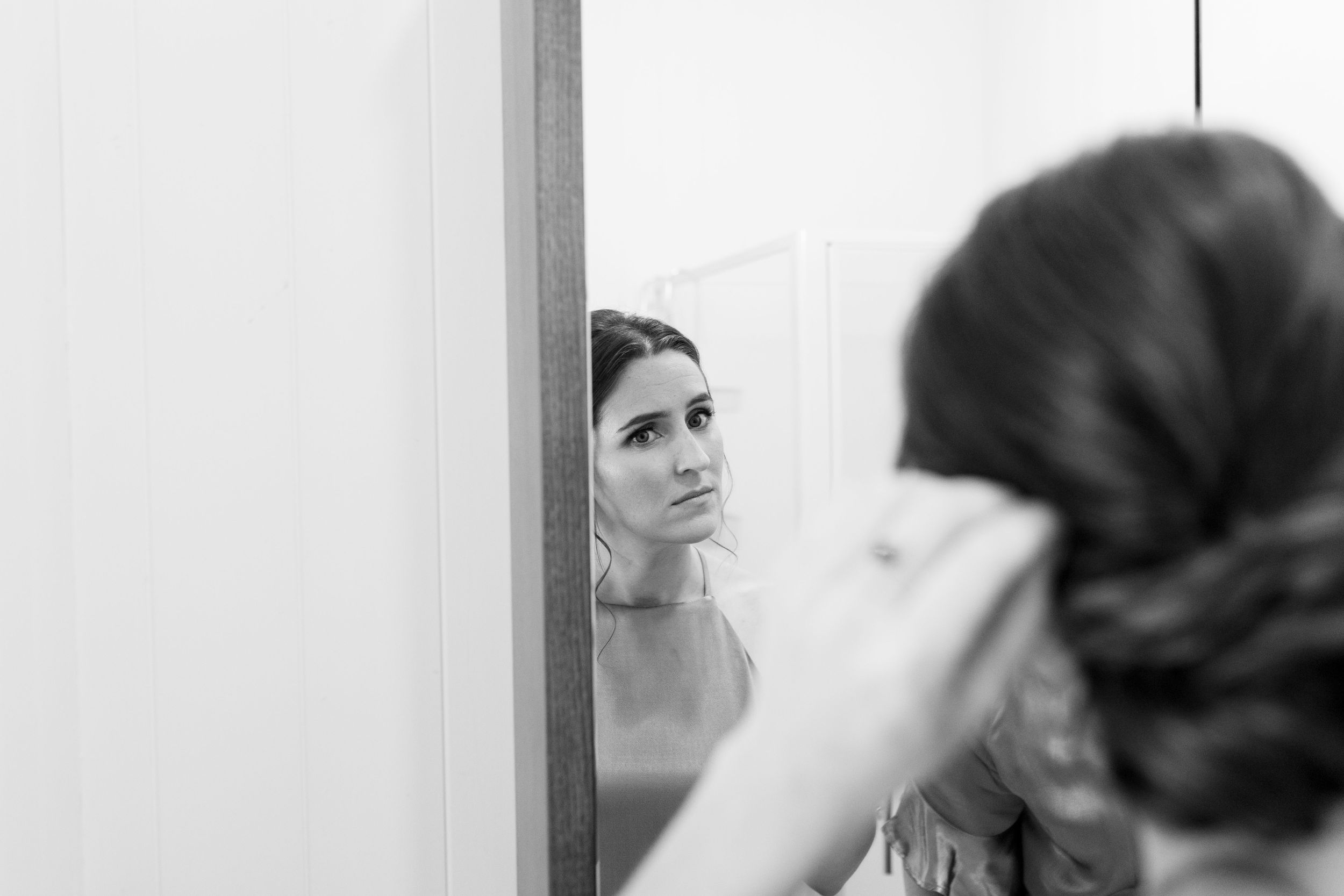 A black and white reflection of someone looking in a mirror while getting ready.
