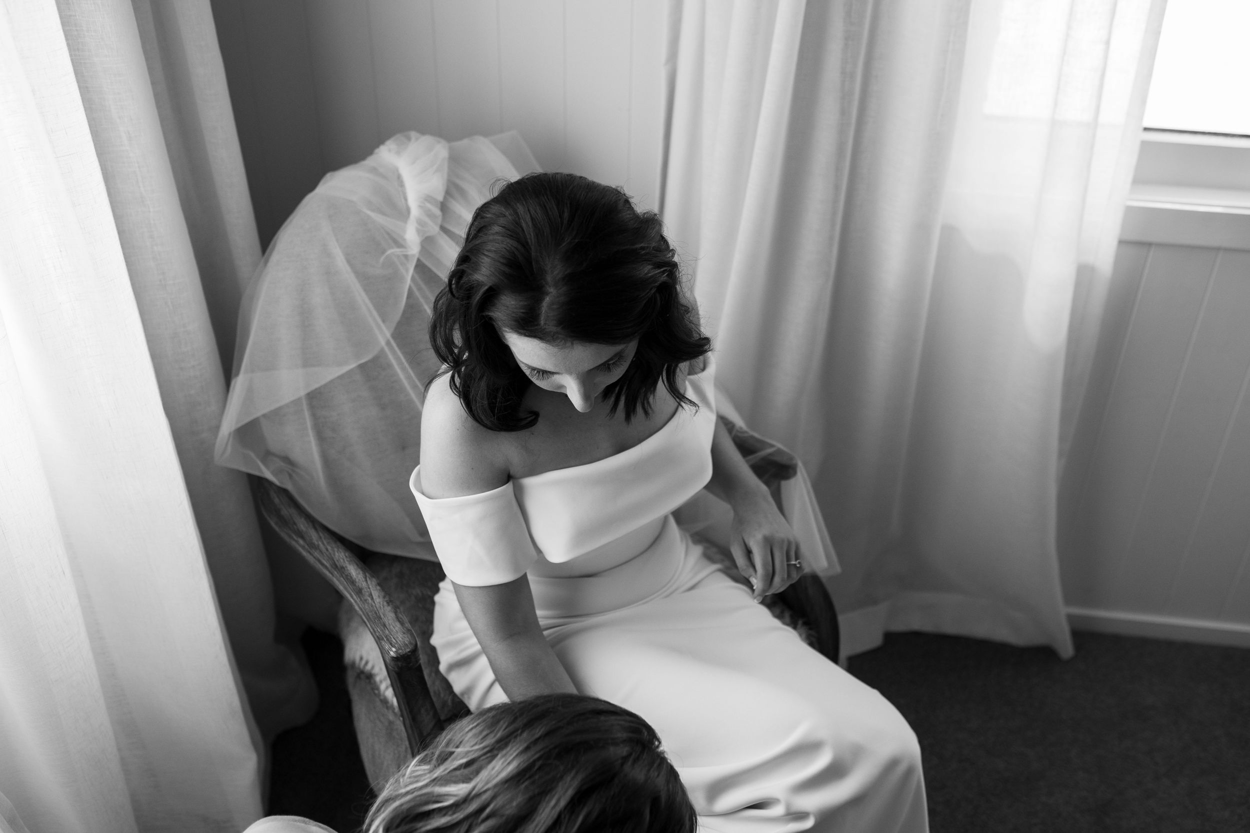 Elegant bridal preparation moment in soft window light.