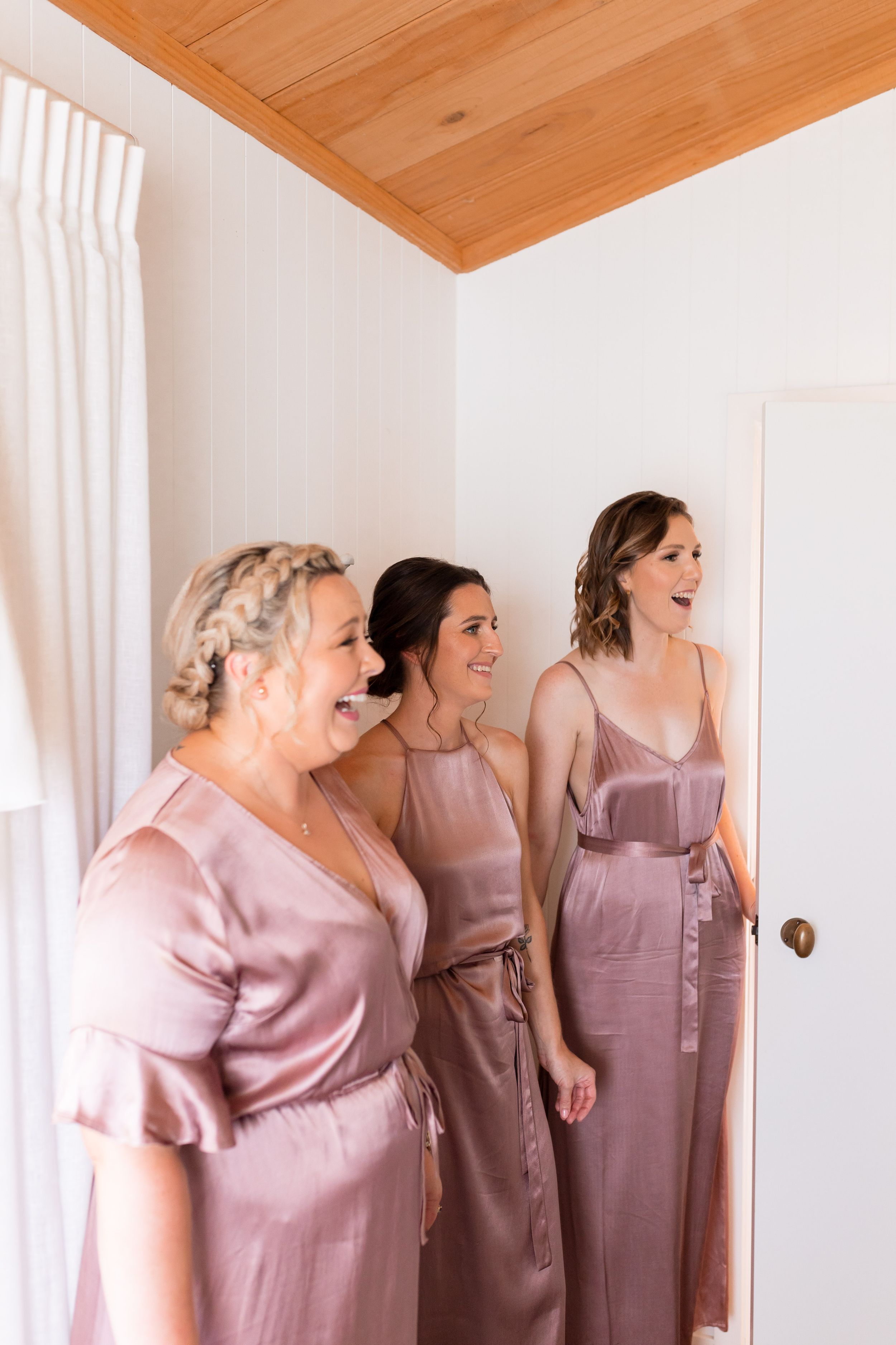 Bridesmaids in dusty rose dresses share a joyful moment.