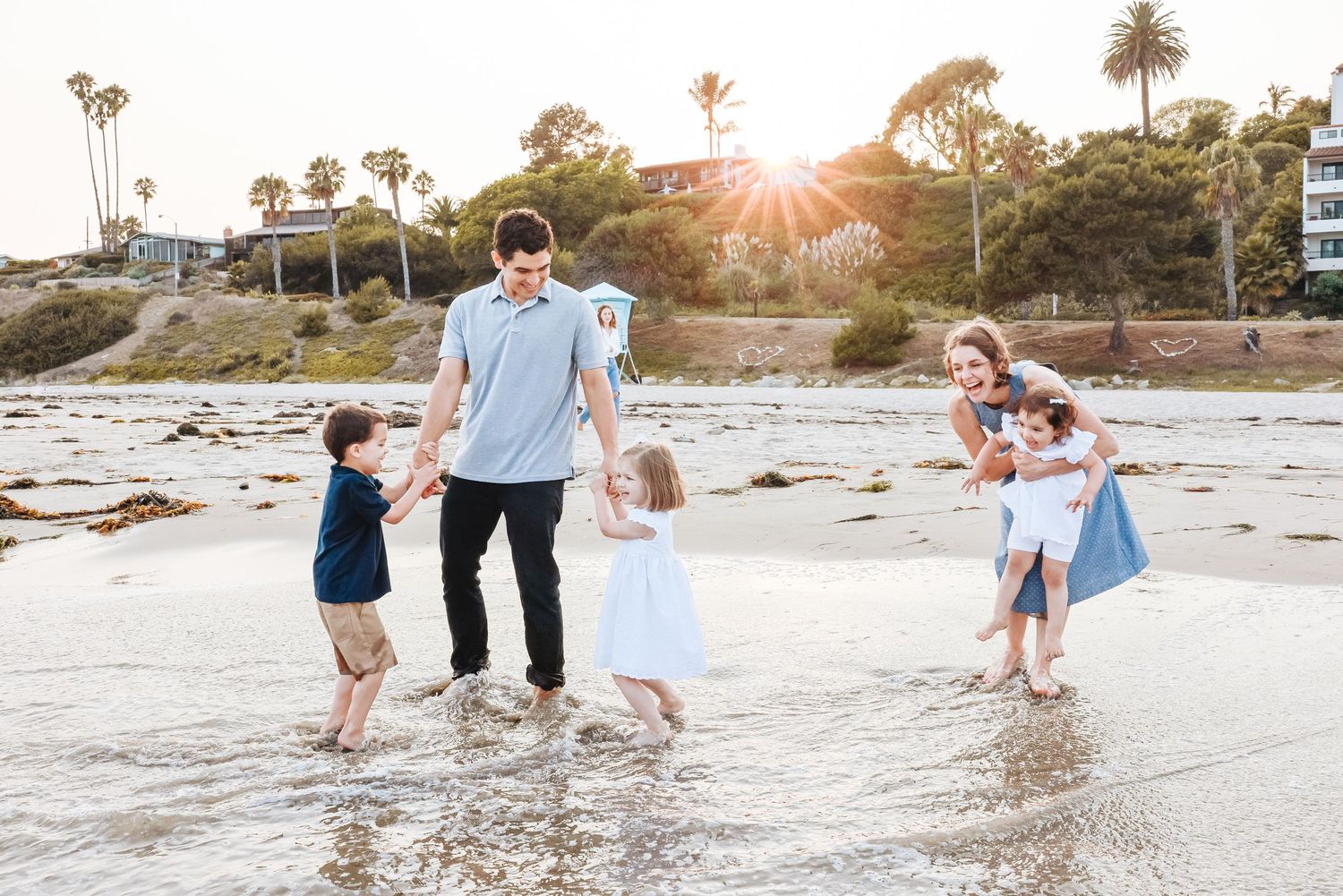 family playing in the waves on beach in Santa Barbara with sun setting in the background