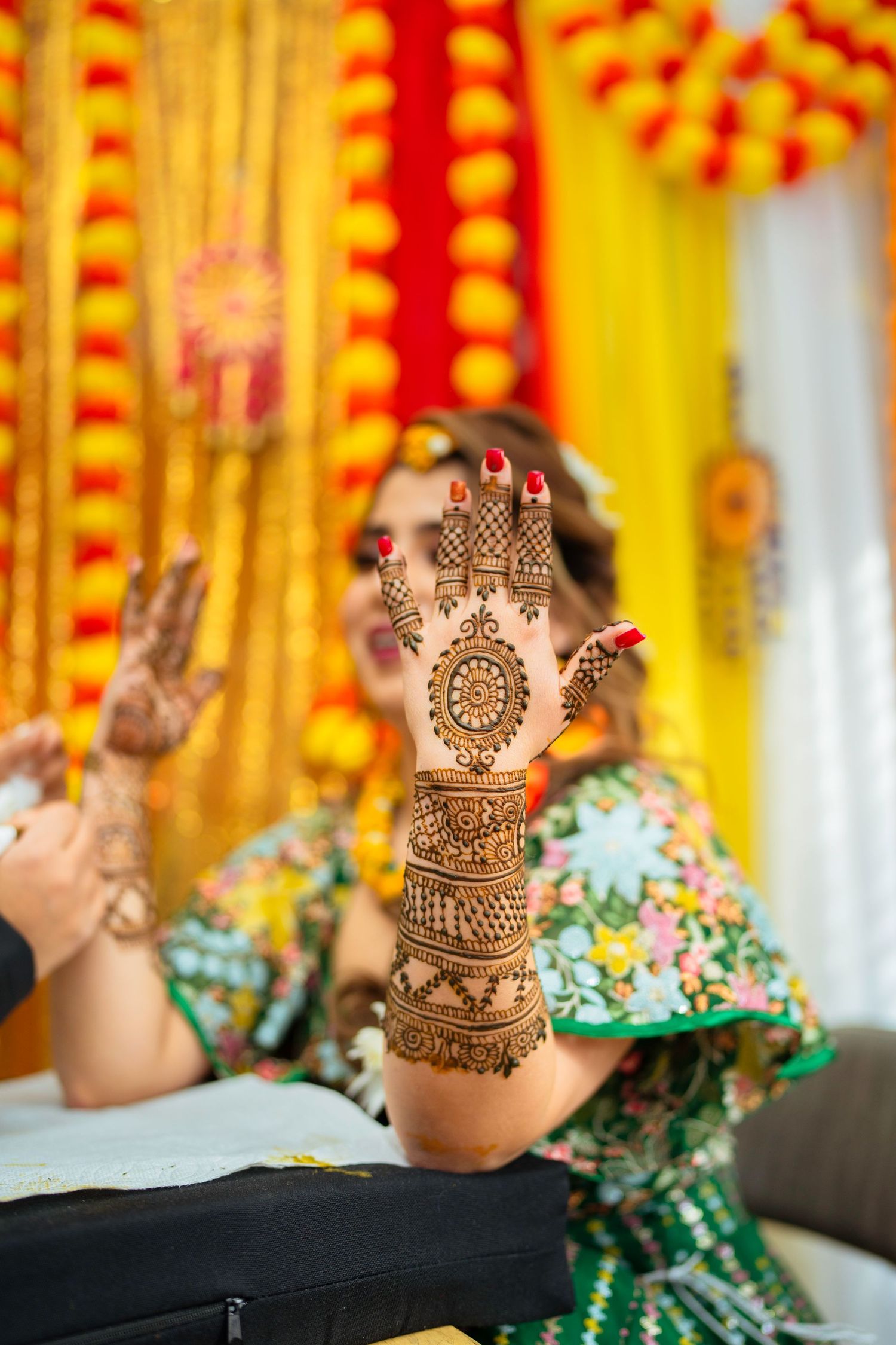Close-up of ornate henna design on hands during traditional ceremony with festive decor.