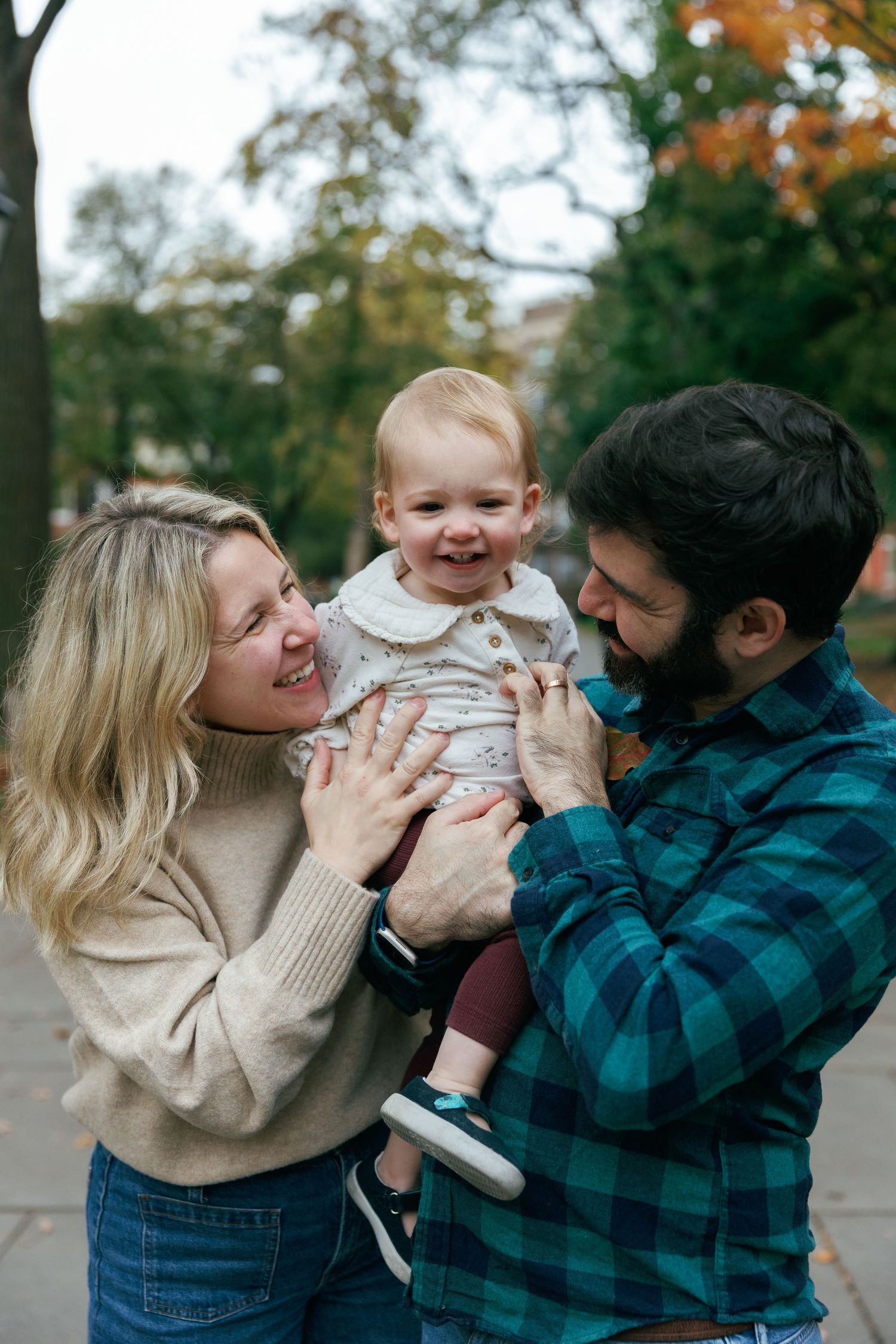 Happy family moment showing joyful interaction outdoors during autumn with child in casual attire.
