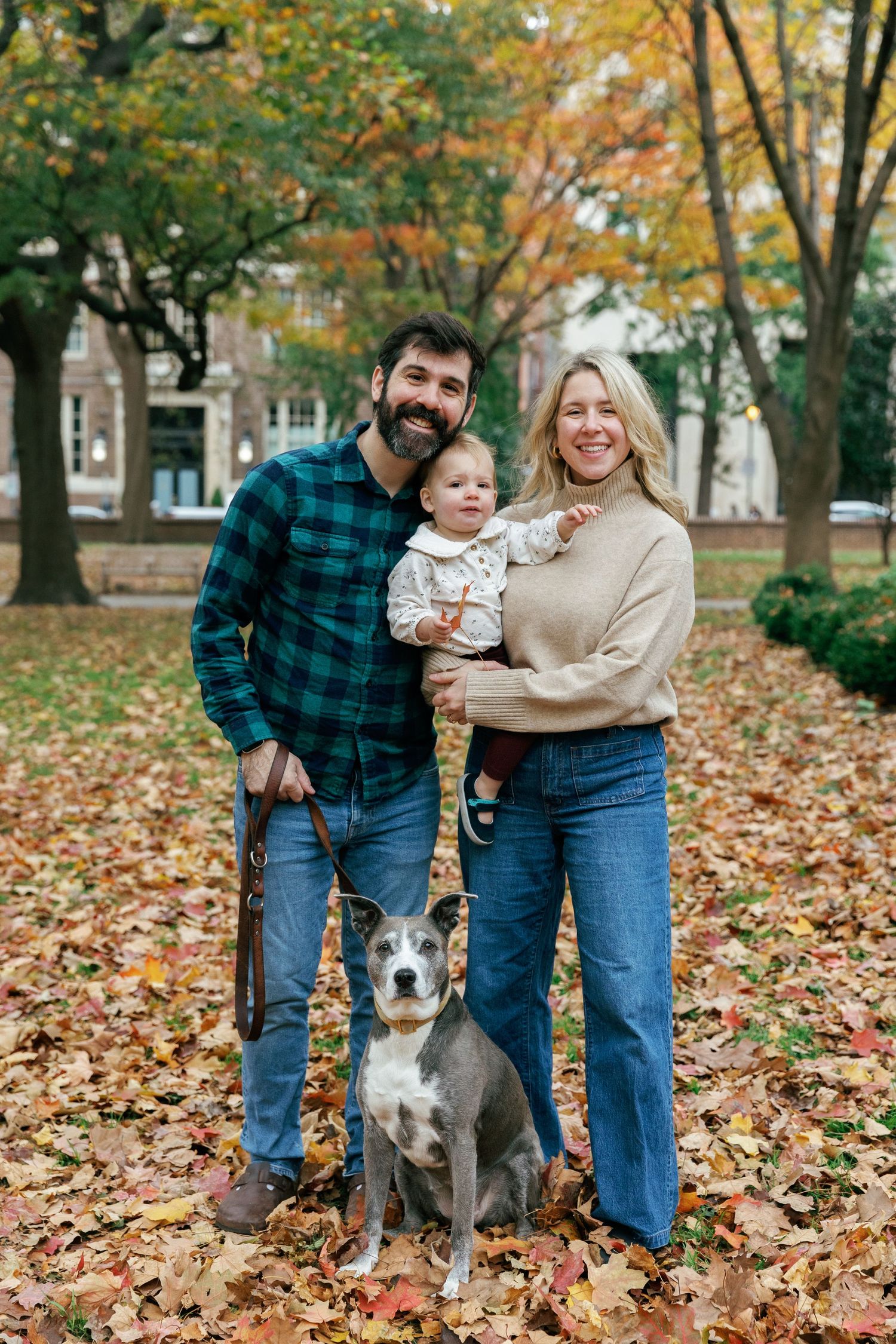 Fall family portrait with dog among colorful autumn leaves.