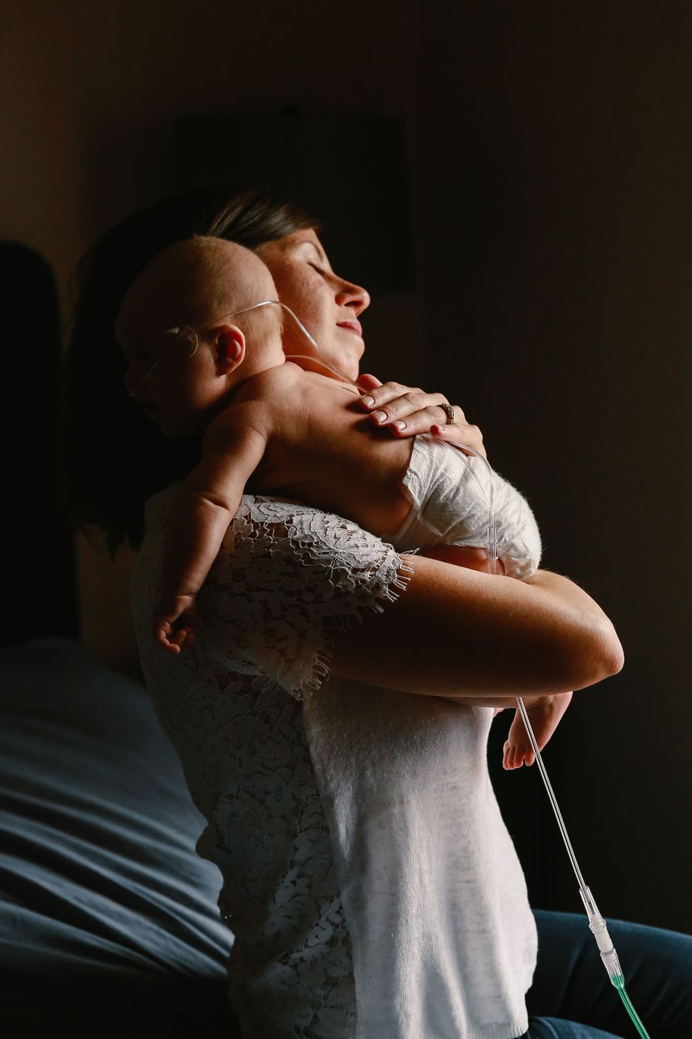 A mother holds their baby in natural light