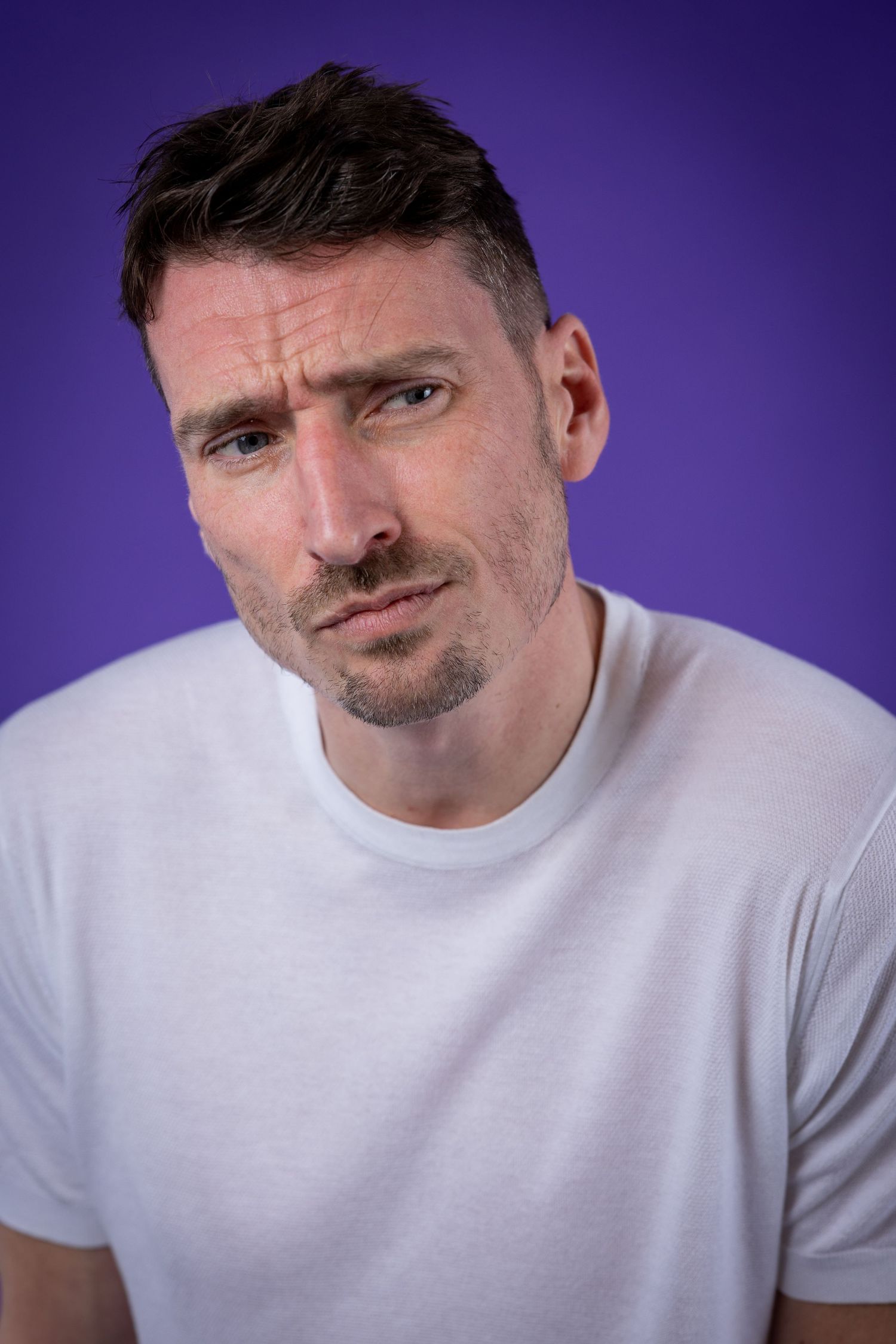 Comedian Alex Howard against a purple background shot in studio in Amy Davies Photography studio in Hove