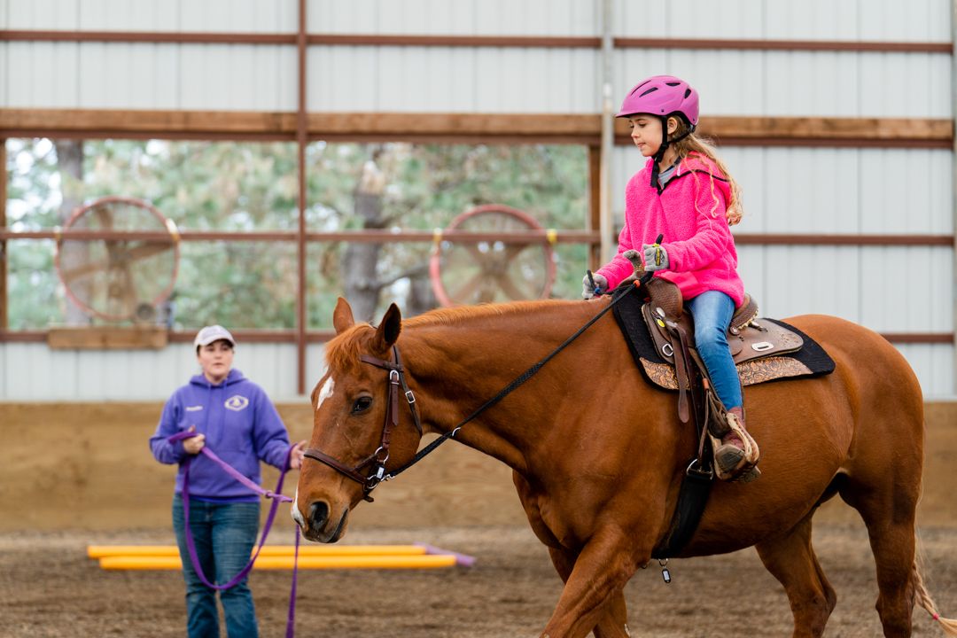 staff helping a girl trot a horse
