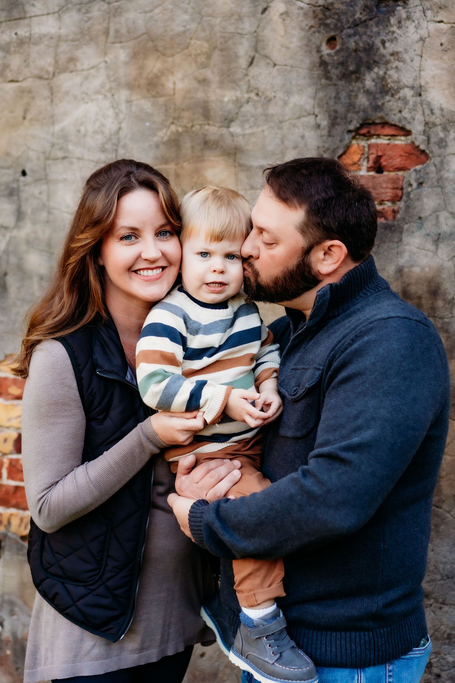 Family portrait against weathered brick wall background.